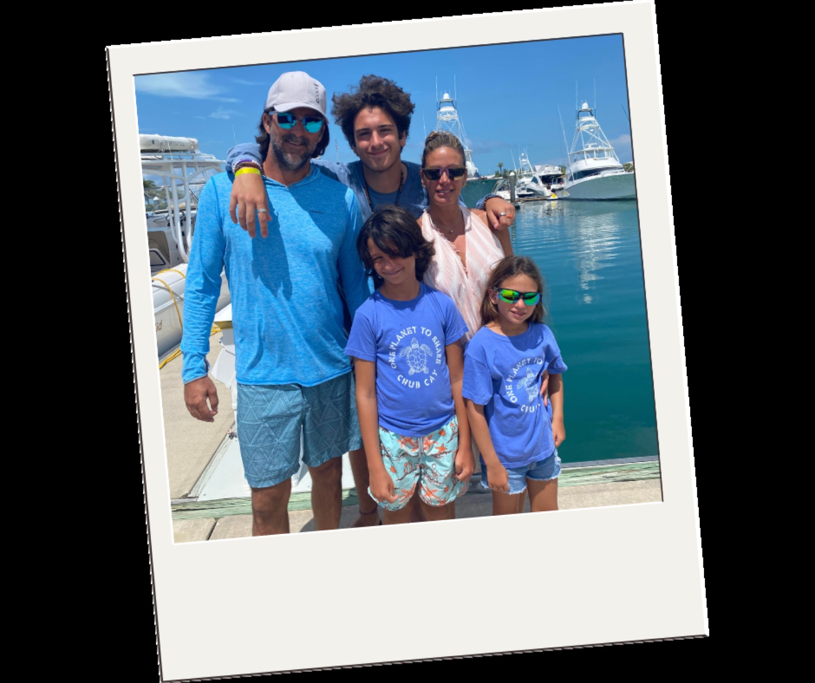 The Bosch family of five standing together on the dock at Chub Cay marina with sportfishing boats behind them