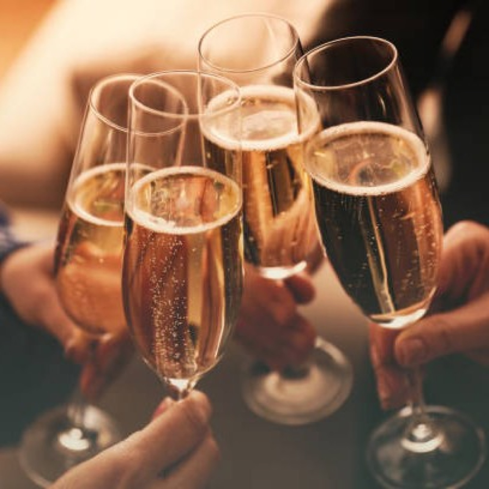 Four hands raising champagne flutes in a toast