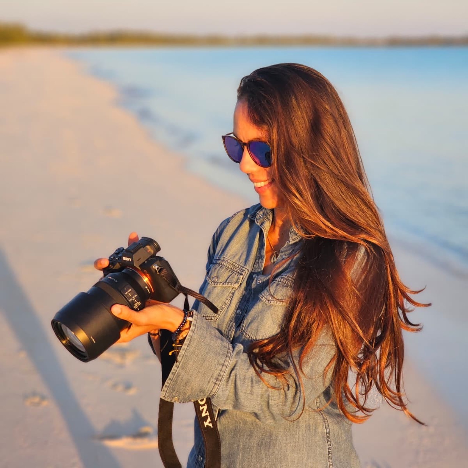 Ana on the beach at golden hour holding her camera
