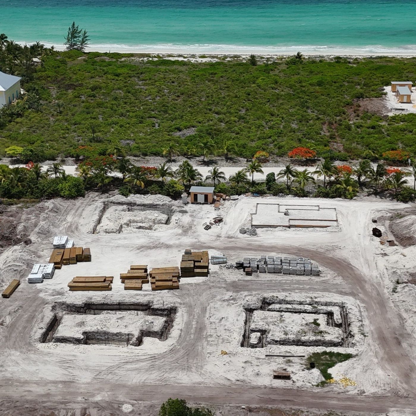 Aerial view of the four demo home construction sites near the beach, with completed foundations and stacked building materials