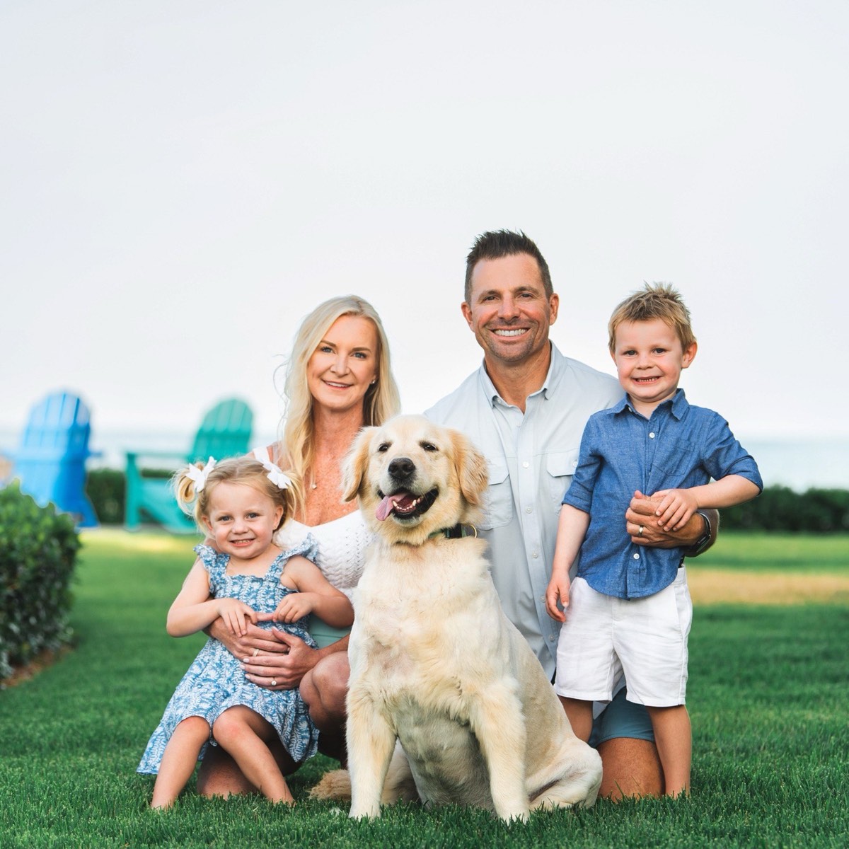 The Naz family with their golden retriever Chub on a seaside lawn