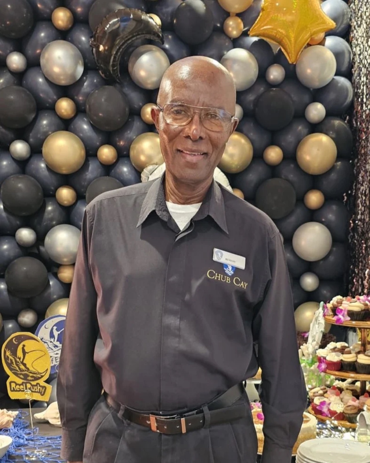 John “Remedy” Rolle in his Chub Cay uniform in front of a balloon backdrop at his celebration
