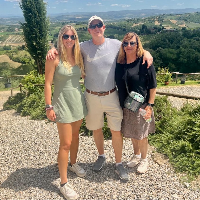 Joe, Colleen and Grace Barbara on a gravel path above vineyards and rolling hills